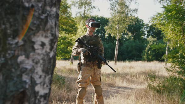 Soldier with Rifle Wearing Virtual Reality Glasses Outdoors