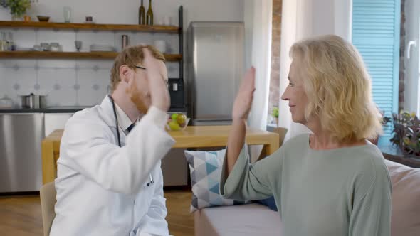 Smiling Young Doctor Giving High Five To Mature Woman