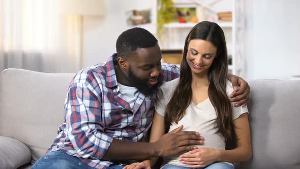 Smiling Afro-American Man Stroking His Pregnant Wife Tummy, Future Parents
