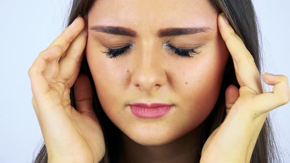 A Young Beautiful Woman Has a Headache and Rubs Her Temples - Face Closeup - White Background