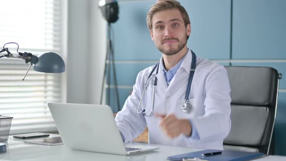Doctor Showing Thumbs Up Sign While Using Laptop at Work