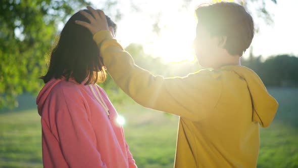 Side View Portrait of Loving Teenage Boyfriend Caressing Hair of Charming Girlfriend Talking Smiling