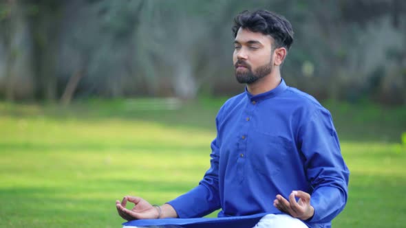 Indian man doing Padmasana or Lotus Yoga Pose in an Indian traditional outfit Kurta Pajama