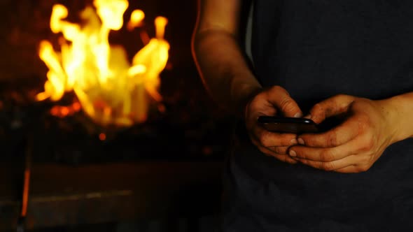 Female metalsmith using mobile phone in factory 4k