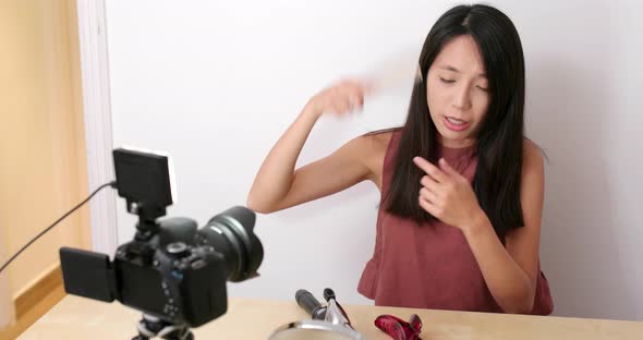 Woman making hair in front of the digital camera to take vlog on social media 