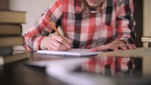 Young student girl makes notes in a notebook, close-up