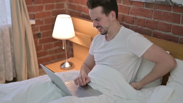 Young Man Having Back Pain While Working on Laptop in Bed