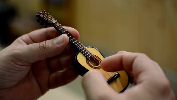 Close  Up of Fingers Playing a Small Toy Guitar