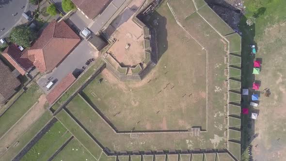 Tourists Walk Along Ground Near Tower and Wall of Galle Fort