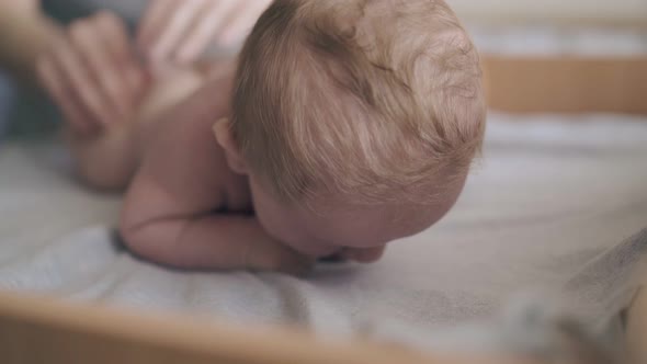 Newborn Boy Lies on Stomach and Enjoys Legs Massage