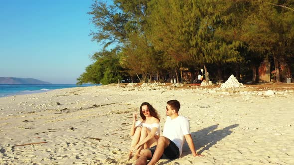 Teenage lovers posing on paradise bay beach vacation by aqua blue water and white sandy background o