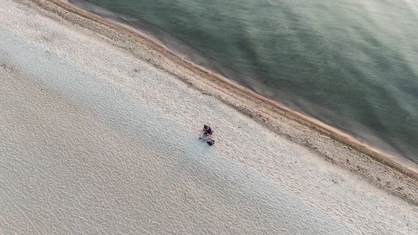 Man playing the guitar on the beach at sunset - aerial view