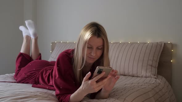 Woman Lying in Bed with Phone