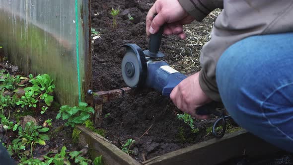 Closeup of a Man with an Angle Grinder Cutting an Old Metal Greenhouse