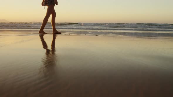 Woman with arms outstretched walking on beach