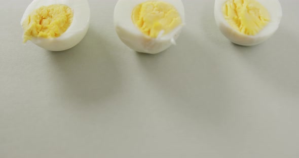 Video of close up of three halves of hard boiled eggs on grey background