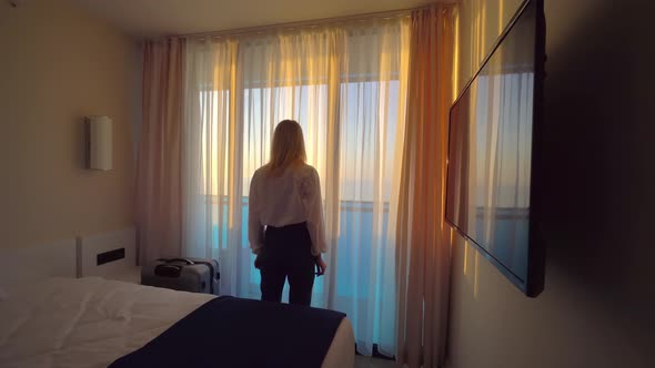 Portrait of tourist visiting hotel, standing at window and admiring beautiful