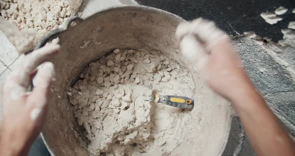 First Person View Man Hands Closeup Adding Gravel to Cement Mortar and Mixing It