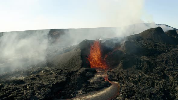 Aerial flight towards spectacular volcanic eruption with spewing lava from crater. Close up flyover.