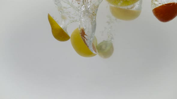 Fresh sectioned fruits dropped into water, Ultra Slow Motion alt