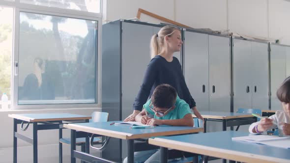 Friendly School Teacher Giving Help To Pupil Boy