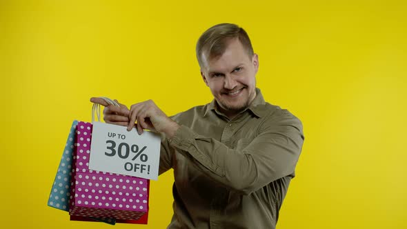 Man Showing Up To 30 Percent Off Inscription and Shopping Bags, Looking Satisfied with Low Prices