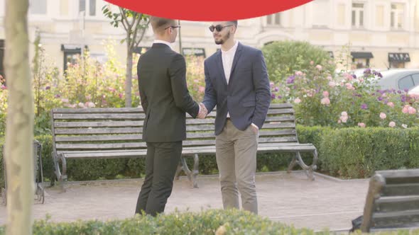 Two Young Caucasian Men in Suits Meeting Outdoors and Shaking Hands As Prohibition Sign Appearing