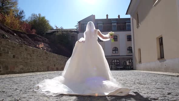 The Bride in a Beautiful Luxurious Dress with a Bouquet of Flowers in Her Hands She is on a Running