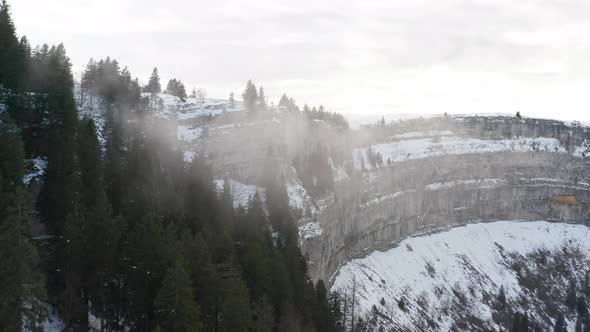 Drone flying through thin clouds in snowcovered mountains