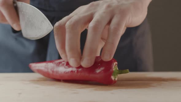 Men Chef Turns on Pepper with Knife for Salad in the Kitchen at Home Cooking