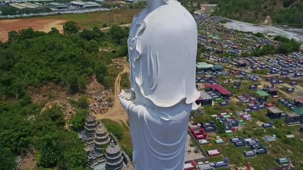 Flycam Shows White Buddha Statue Against Town and Landscape