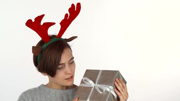 Happy Woman in Reindeer Antlers Headband Looking at Her Christmas Present