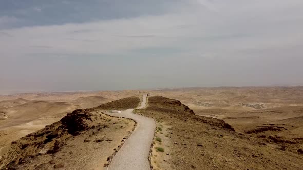 aerial forward slow drone shot of an empty long trail on the top of a mountain, surrounded by endles