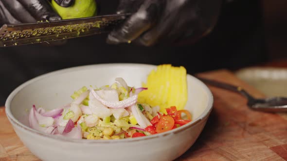 Preparation of Ceviche - slow motion close up shot of a chef holding grater, grating lime into a bow