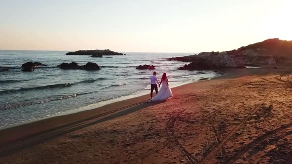 Loving Couple Walking on Beach At Sunset