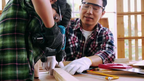 Carpenter Asian man teaching his son how to work with wood in workshop.