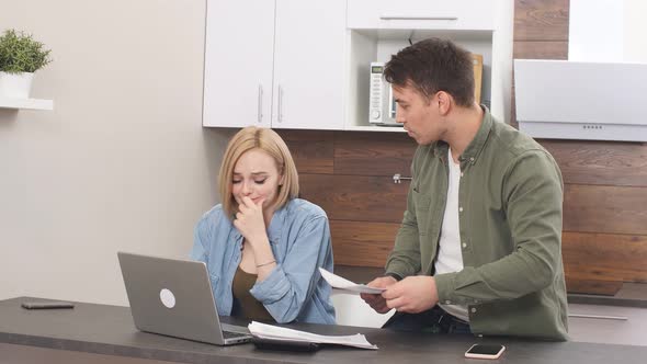 Disappointed Sad Couple Upset with Finance at Home, Sitting with Laptop and Papers