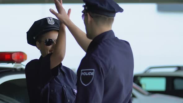 Smiling Police Officers Giving High-Five, Rejoicing Patrol Day Without Crimes