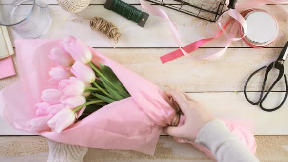 Step by step. Florist wrapping pink tulips in bouquet.