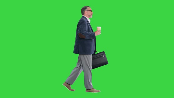 Senior Businessman Walking and Holding in a Hand a Cup of Coffee on a Green Screen Chroma Key