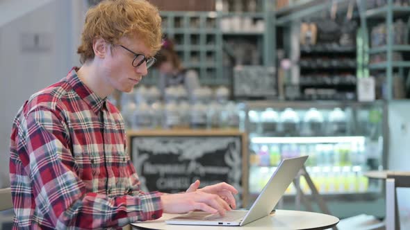 Professional Young Redhead Man in Cafe Using Laptop