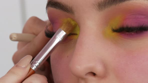 Professional Makeup Artist Makes Bright Fashion Makeup to Model in Yellow and Pink Eyeshadows on the