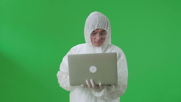 Asian Man Wear Uniform Ppe Holding And Working With Laptop Computer In The Green Screen Studio