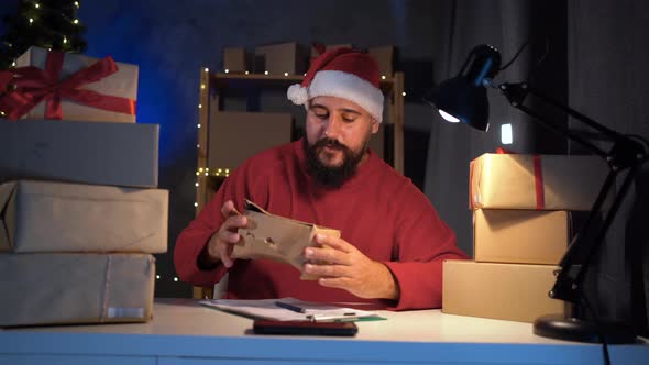 Dropshipping Owner Indian Man Santa Claus Works at Night in His Home Office on Laptop Writes the