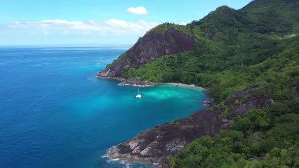 Aerial view of a small luxury sailboat anchored in a paradise bay, Seychelles.