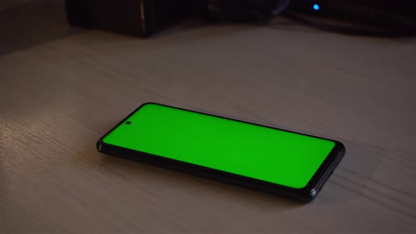 A Mobile Phone With A Green Screen Is Lying On The Table