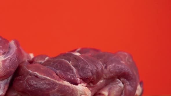 Close-up of a bloody piece of raw red meat on a bright orange background