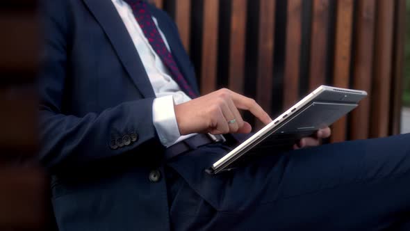 Close Up Businessman in Official Dark Blue Suit Sits on Bench in Park Before Meeting with Partners