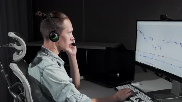 Young Man Using Headset with Microphone Working Online Late at Night