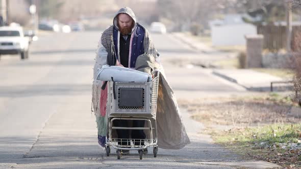 Homeless man pushing shopping cart down the street